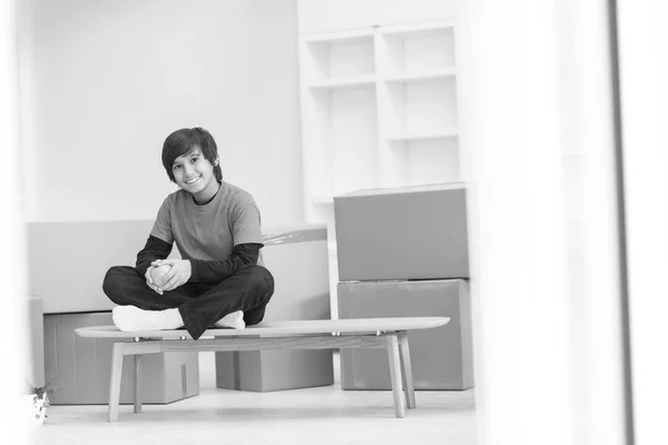 Menino sentado na mesa com caixas de papelão ao seu redor — Fotografia de Stock