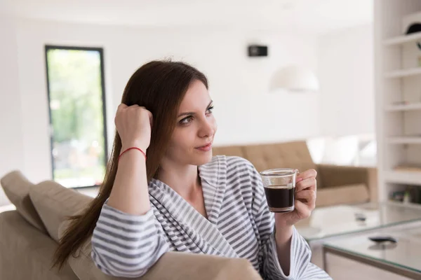 Jonge vrouw in een badjas genieten van koffie in de ochtend — Stockfoto