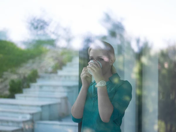 Mladá žena pít ráno kávu u okna — Stock fotografie