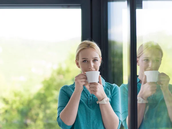 Jovem mulher bebendo café da manhã pela janela — Fotografia de Stock
