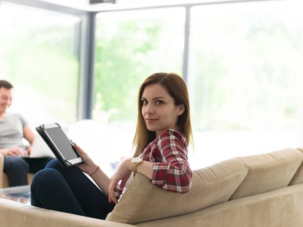 Pareja relajante en casa con tabletas y computadoras portátiles — Foto de Stock