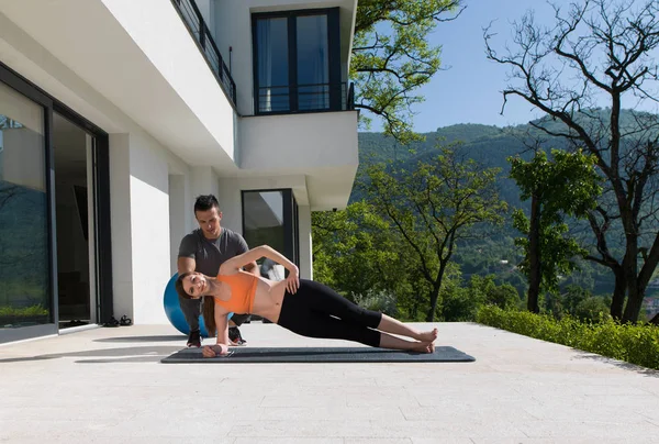 Femme avec entraîneur personnel faisant des exercices de yoga le matin — Photo