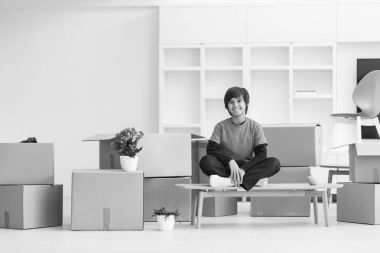 onun etrafında karton kutular ile masaya oturan çocuk