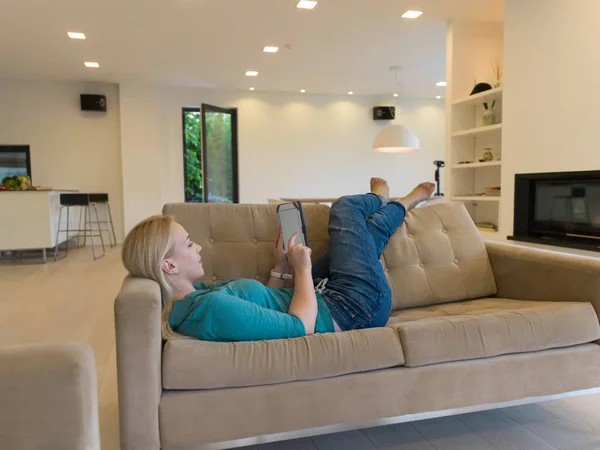 Женщина на диване с помощью планшетного компьютера — стоковое фото