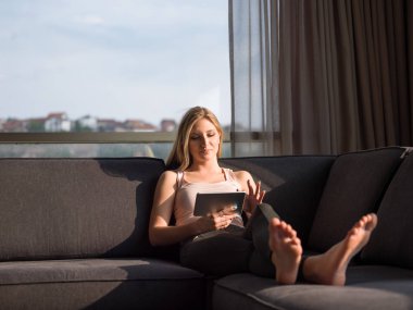 Evde kanepede tablet kullanan kadın