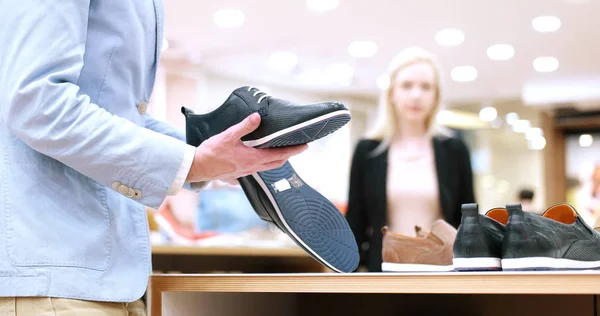 Hombre elige zapatos en tienda de zapatos — Foto de Stock