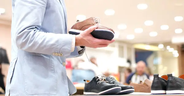 Homem escolhe sapatos na loja de sapatos — Fotografia de Stock