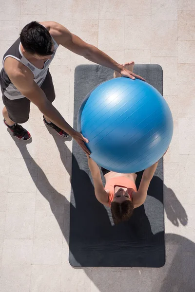 Mujer y entrenador personal haciendo ejercicio con pelota de pilates — Foto de Stock