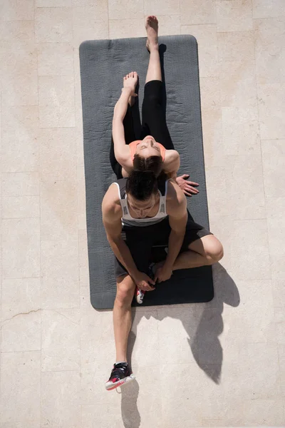 Vrouw met personal trainer doet ochtend yoga oefeningen top vie — Stockfoto