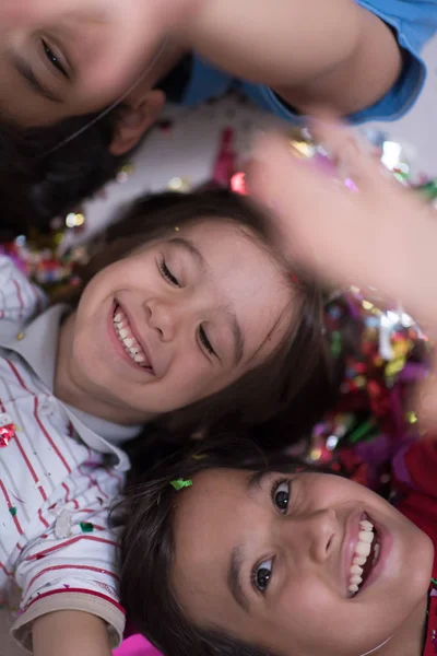 Дети дуют конфетти, лежа на полу — стоковое фото