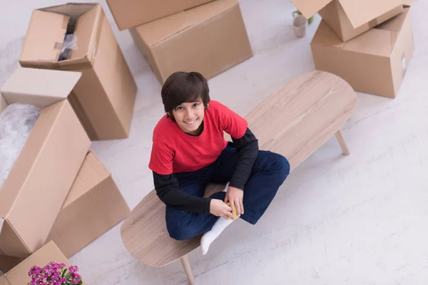 Menino sentado na mesa com caixas de papelão em torno dele top vie — Fotografia de Stock