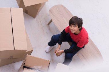 En iyi çevresindeki karton kutular ile masaya oturan çocuk vie