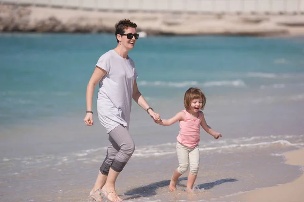 Mutter und Tochter rennen am Strand — Stockfoto