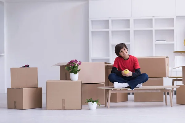 Menino sentado na mesa com caixas de papelão ao seu redor — Fotografia de Stock