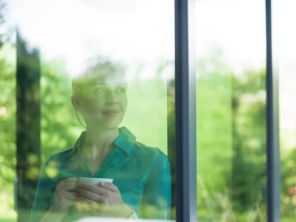 Jonge vrouw drinken's ochtends koffie bij het raam — Stockfoto