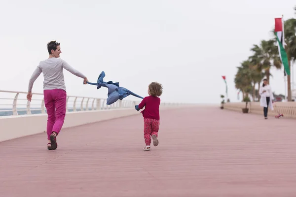 Mor och söt liten flicka på strandpromenaden vid havet — Stockfoto