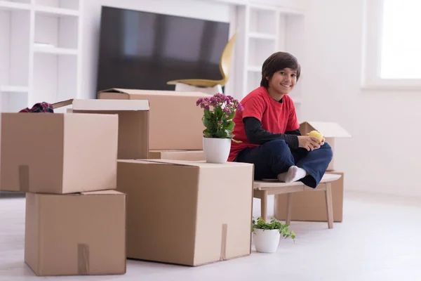 Boy sitting on the table with cardboard boxes around him — Stock Photo, Image