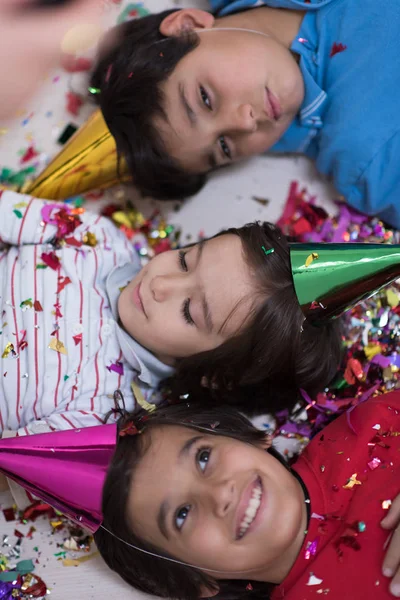 Děti foukání konfety vleže na podlaze — Stock fotografie