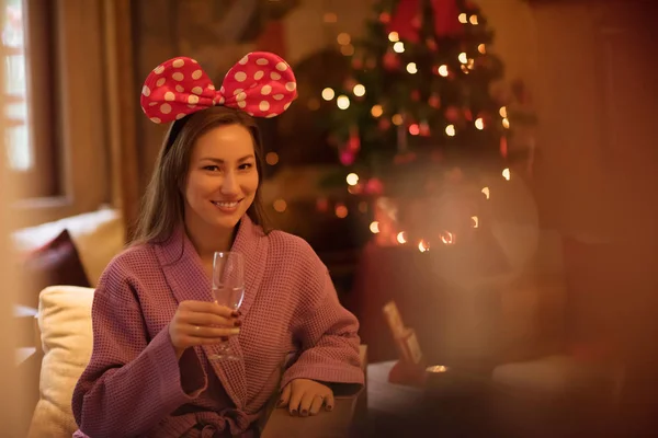 和放松概念美丽的年轻女子在浴袍喝香槟在温泉在假日灯光背景 — 图库照片