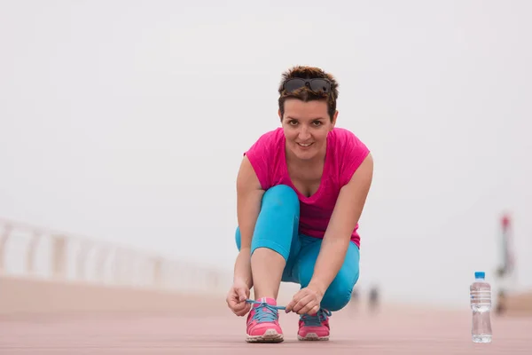 Jonge vrouw koppelverkoop schoenveters aan sneakers — Stockfoto