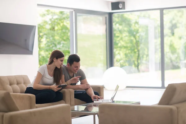 Пара розслабляється вдома з планшетними комп'ютерами та ноутбуками — стокове фото