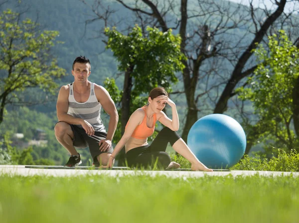 Donna con personal trainer che fa esercizi mattutini di yoga — Foto Stock