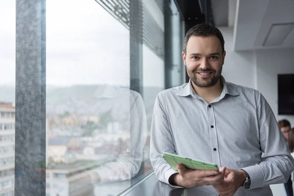 Empresario usando tableta en edificio de oficinas por ventana — Foto de Stock