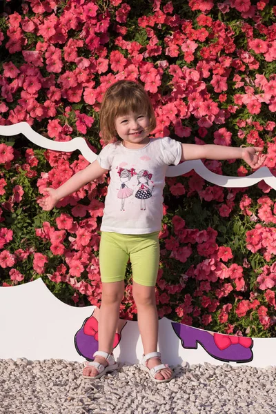Το μικρό χαριτωμένο κορίτσι σε έναν κήπο λουλουδιών — Φωτογραφία Αρχείου