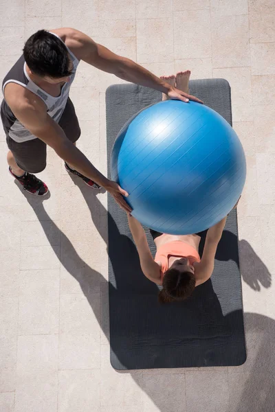 Mujer y entrenador personal haciendo ejercicio con pelota de pilates — Foto de Stock