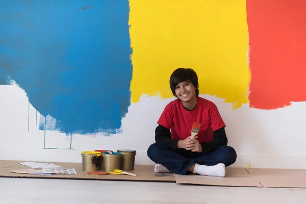 Мальчик-художник отдыхает после покраски стены — стоковое фото