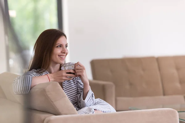 Mujer joven en un albornoz disfrutando del café de la mañana —  Fotos de Stock