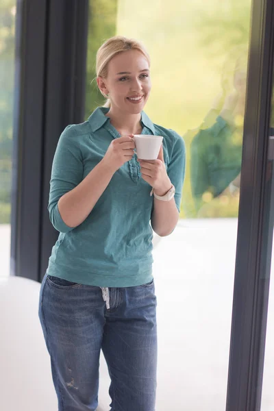 Ung kvinna dricka morgonkaffe vid fönstret — Stockfoto