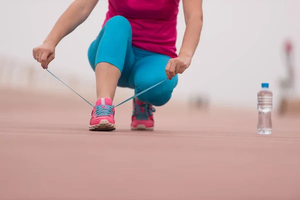 Junge Frau bindet Schnürsenkel an Turnschuhe — Stockfoto