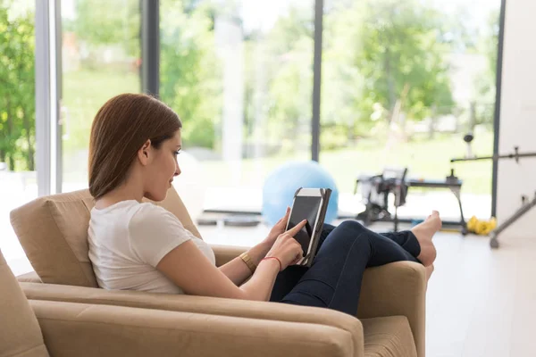 Žena sedí na pohovce s tabletovým počítačem — Stock fotografie