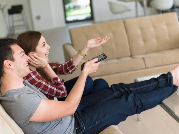 Jovem casal no sofá assistindo televisão — Fotografia de Stock