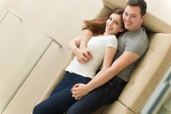 Jovem casal bonito abraçando no sofá — Fotografia de Stock