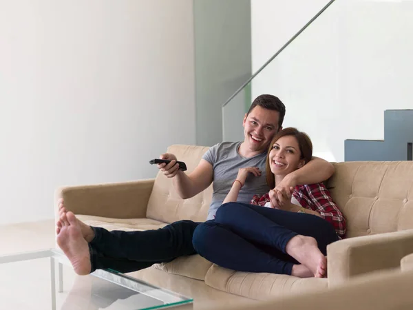 Jong (echt) paar op de bank tv-kijken — Stockfoto