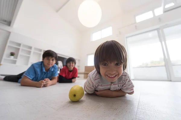 Jungs amüsieren sich mit einem Apfel auf dem Boden — Stockfoto