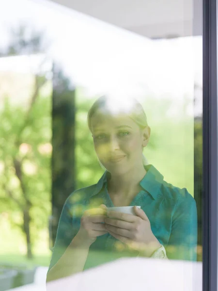 Giovane donna che beve caffè mattutino alla finestra — Foto Stock