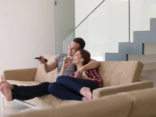 Pareja joven en el sofá viendo la televisión —  Fotos de Stock