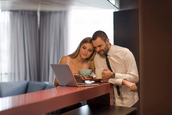 Una giovane coppia si prepara per un lavoro e utilizza un computer portatile — Foto Stock