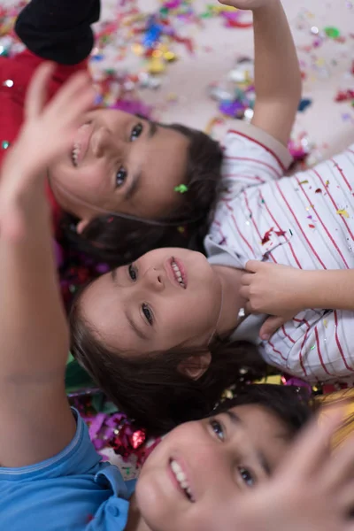 床に横になっている間にコンフェッティを吹いてパーティーを祝う幸せな子供たち — ストック写真