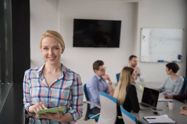 İş kadını pencere kenarındaki kurumsal ofiste dijital tablet kullanıyor