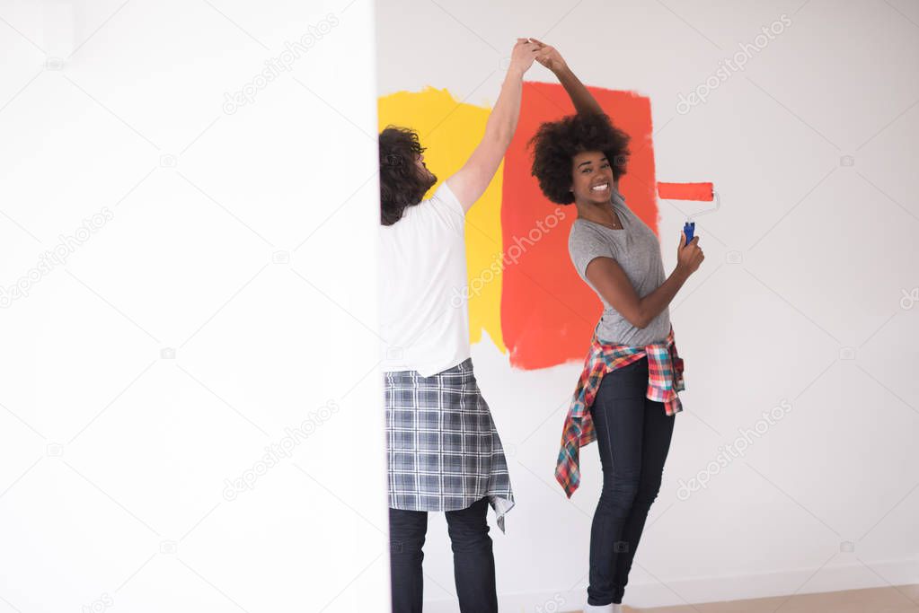 multiethnic couple painting interior wall