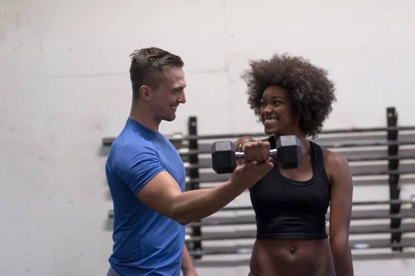 Negro mujer haciendo bíceps rizos con fitness trainer —  Fotos de Stock