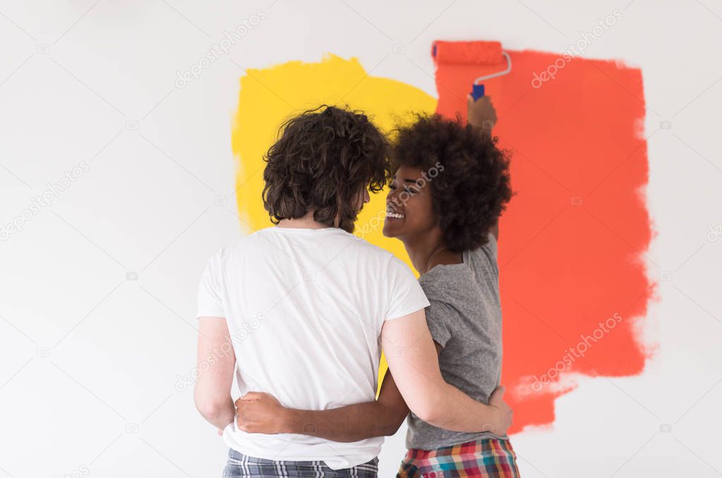 multiethnic couple painting interior wall