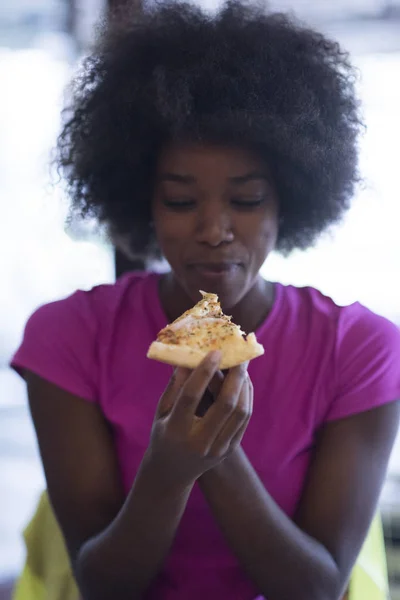 Donna con acconciatura afro mangiare gustosa fetta di pizza — Foto Stock