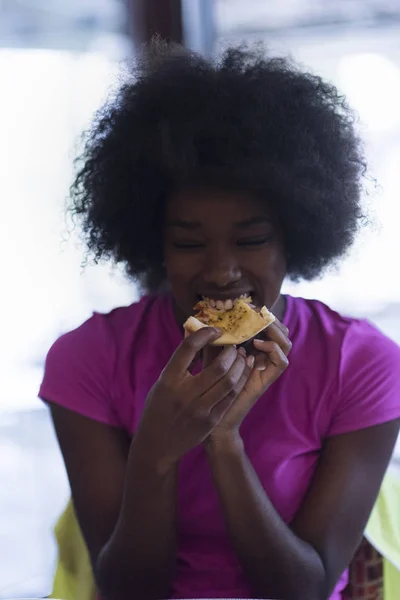 Mulher com penteado afro comer saborosa fatia de pizza — Fotografia de Stock