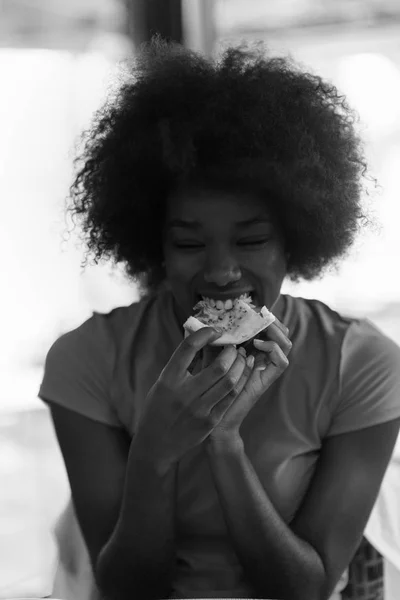 Donna con acconciatura afro mangiare gustosa fetta di pizza — Foto Stock