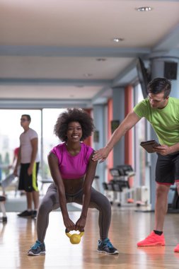 Spor salonunda kişisel antrenörle ağırlık çalışması